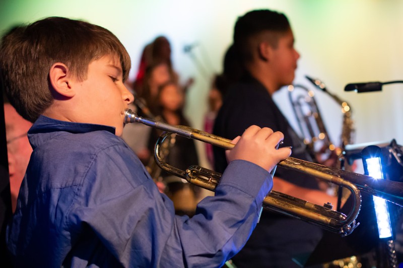 A young boy plays a trumpet.