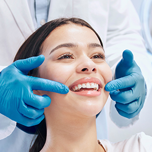 A woman smiles while a dentist points at the corners of her mouth.