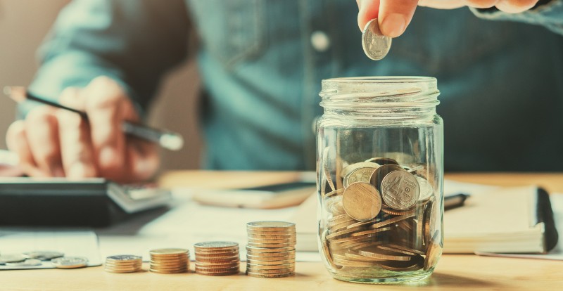 person dropping change in a jar