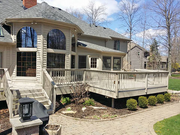 A home with tan siding and a large back deck. 