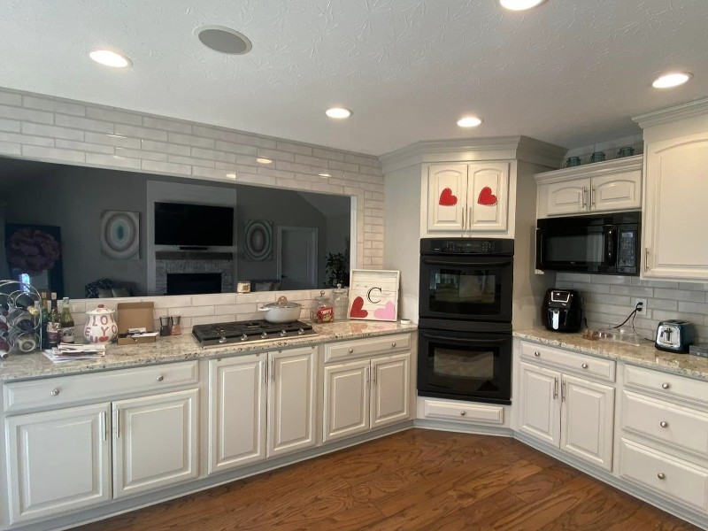 An attractive kitchen with white cabinets and a black stove in the corner.
