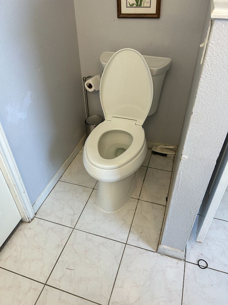 A toilet sits in a walled-off corner of a bathroom.