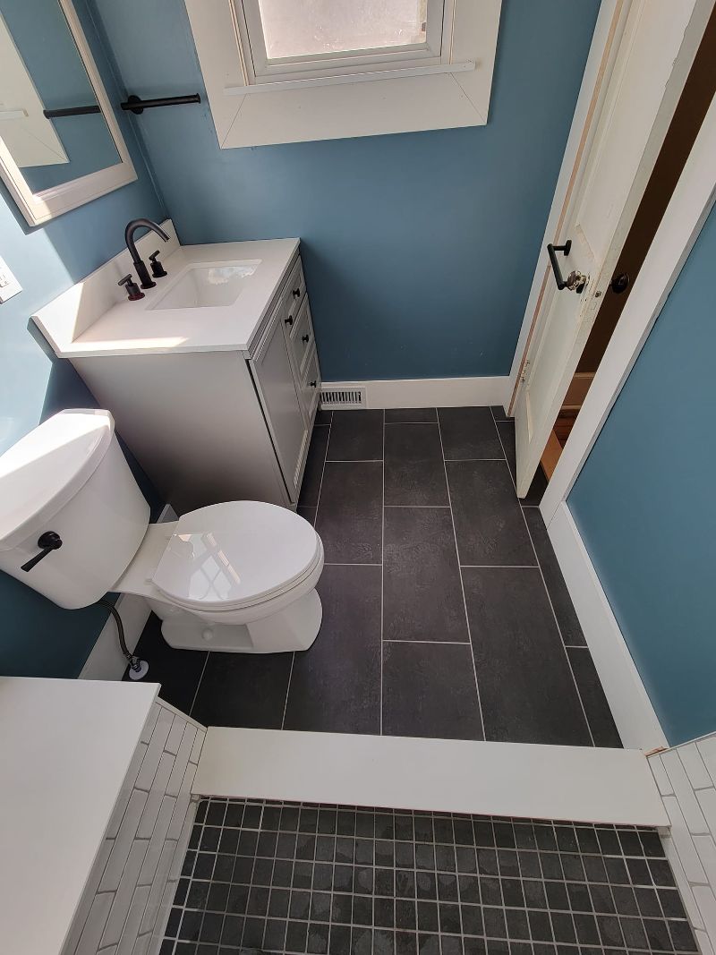 A bathroom makeover with tile flooring and new toilet and vanity.