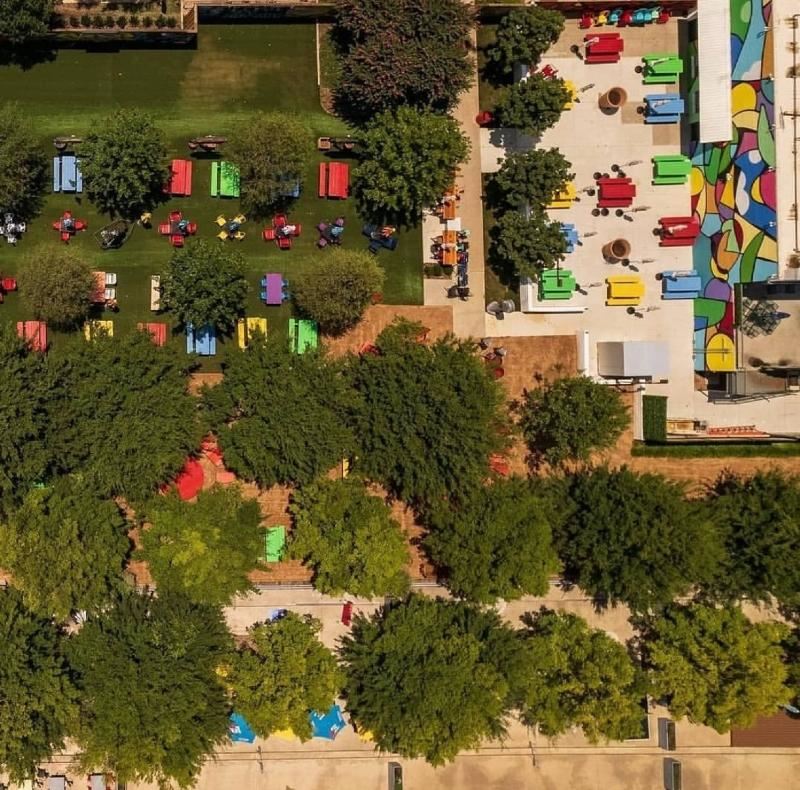 Aerial shot of the Artpark and beer garden, colorful tables and vendor booths dot the grass