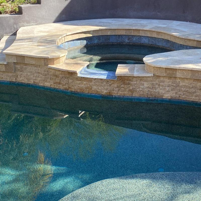 Hot tub leads into pool with waterfall.