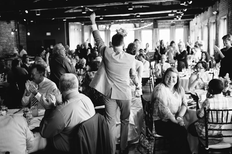 Black and white photo of a wedding reception, crowded room with people clapping