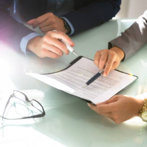 Two people in suits look over paperwork in a folder