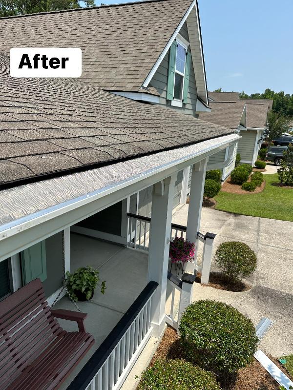 A white gutter system with gutter guard is attached to a shingled roof.