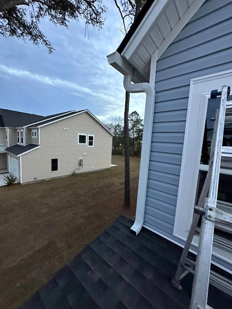 A white gutter system for the second story of a home with a small ladder on the lower roof.