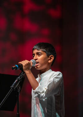 A young boy sings into a microphone.