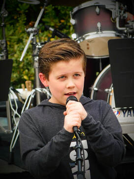 A young boy sings into a microphone.