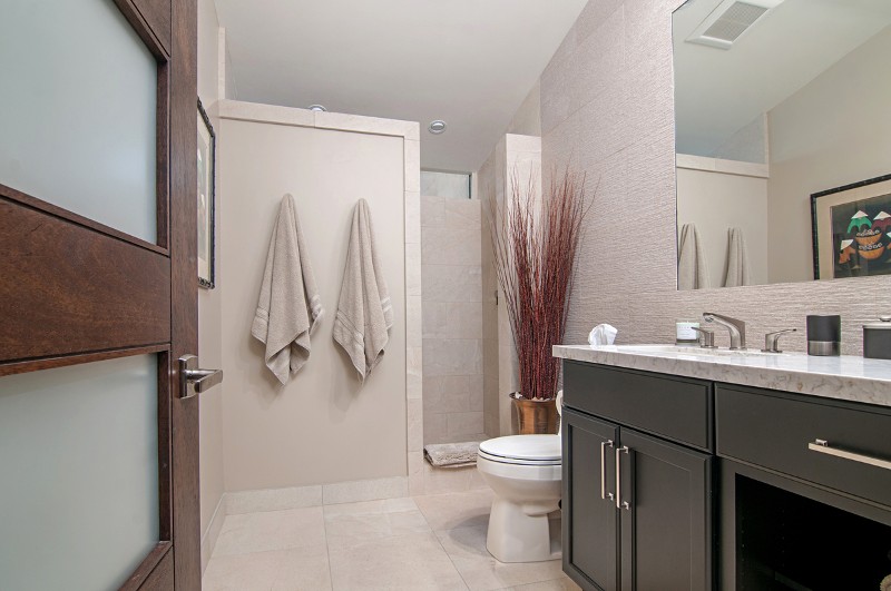 Another angle of the bathroom showing the shower stall, towel hooks, and vanity cabinets