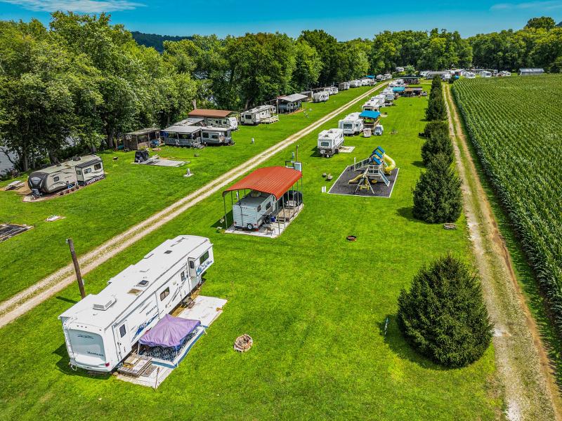 Two motor homes are parked near trees in a campground.