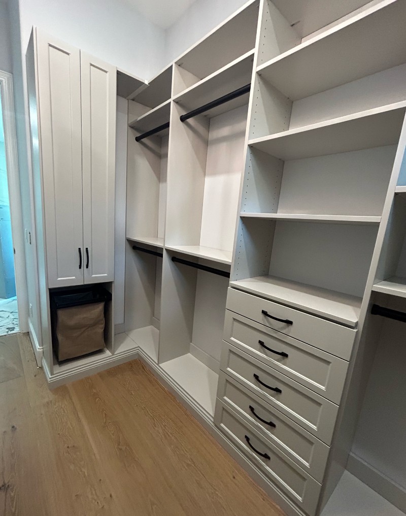 Storage shelves and drawers fit into the corner of a bedroom.