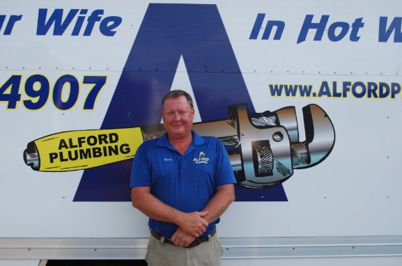 Owner of Alford Plumbing standing by truck.