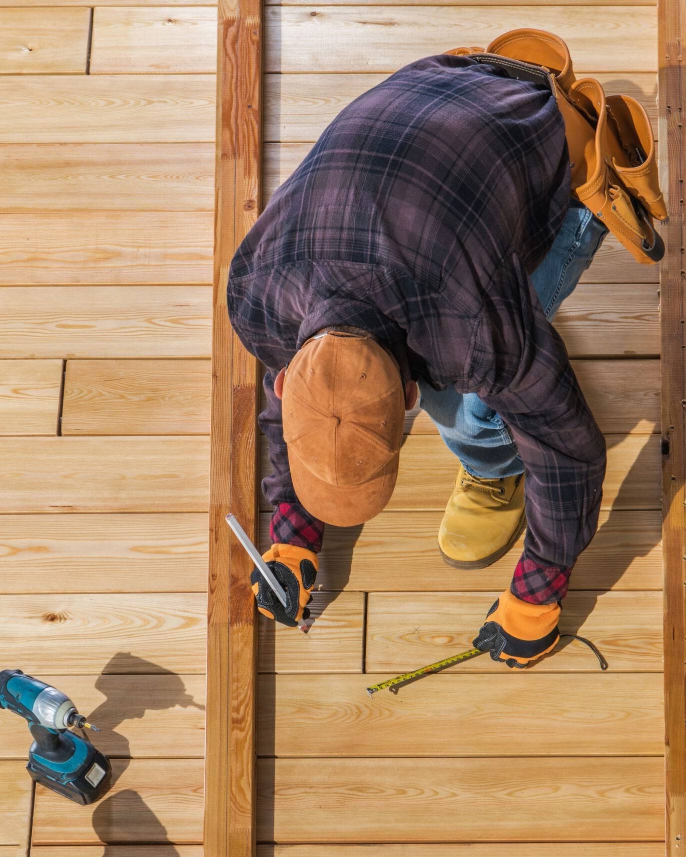 The overhead view of a construction worker marking and measuring on boards.