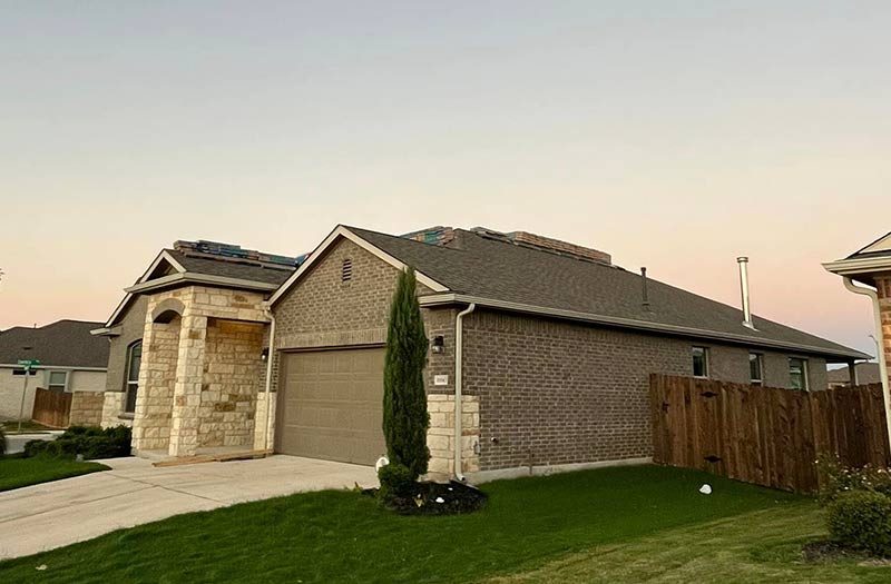 A modern home with a brown shingled roof.