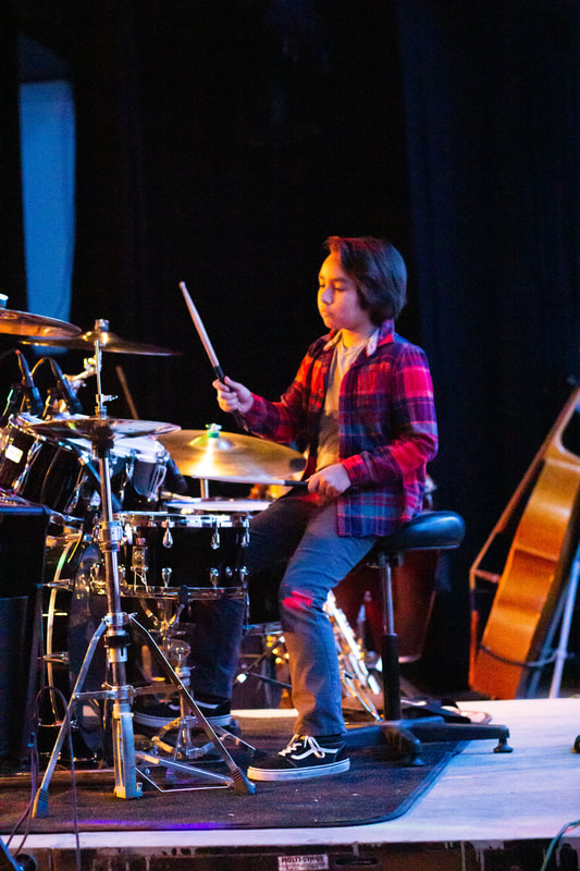 A young boy plays the trap set.