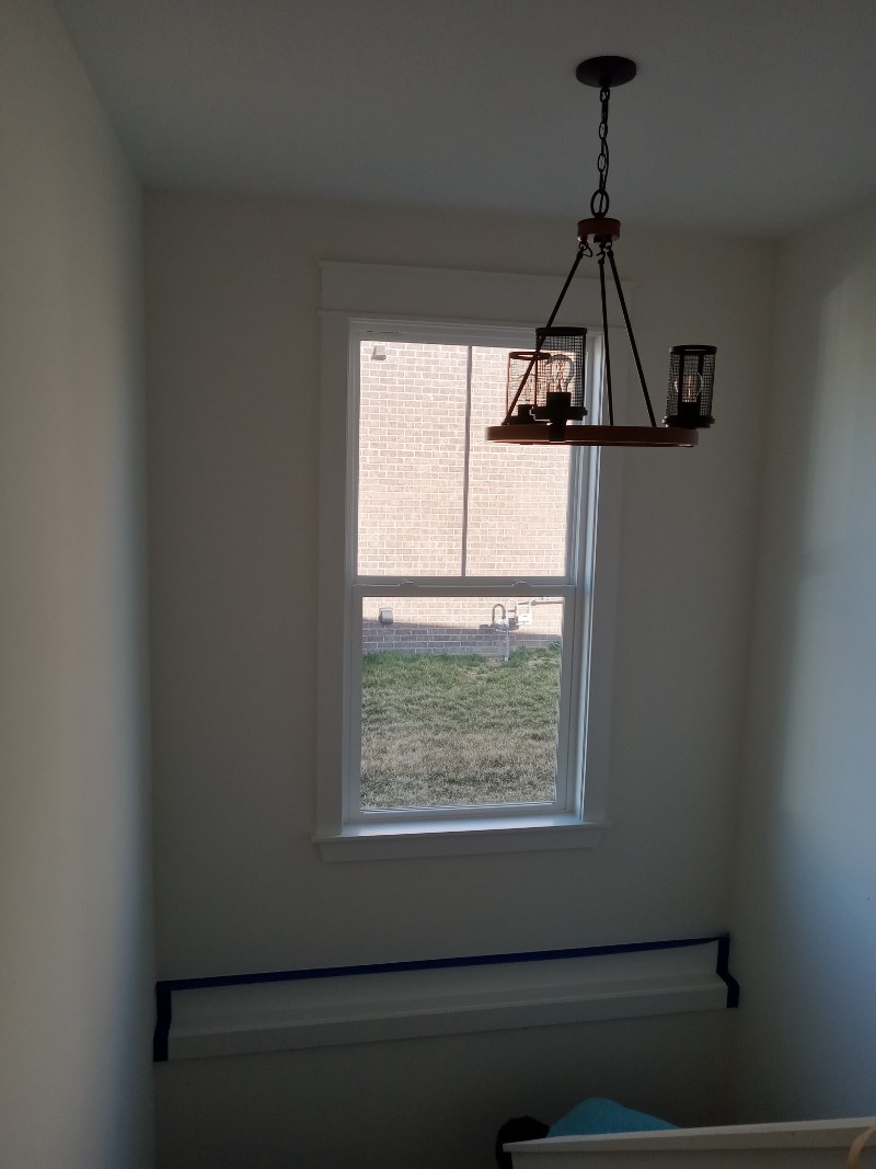 A small room freshly painted and a chandelier hanging from the ceiling.