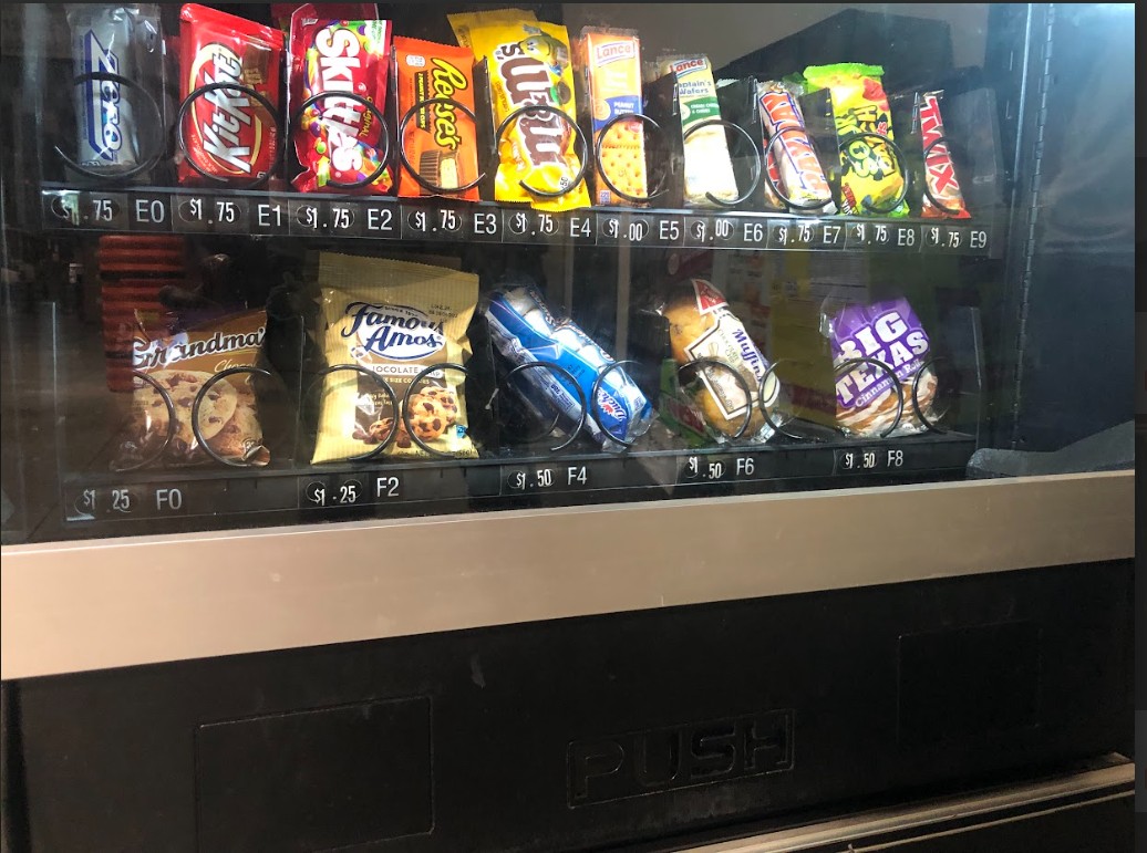 A variety of candy and cookies fill a vending machine.