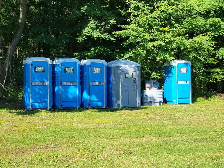 Five portable toilets with a portable sink situated in between them.