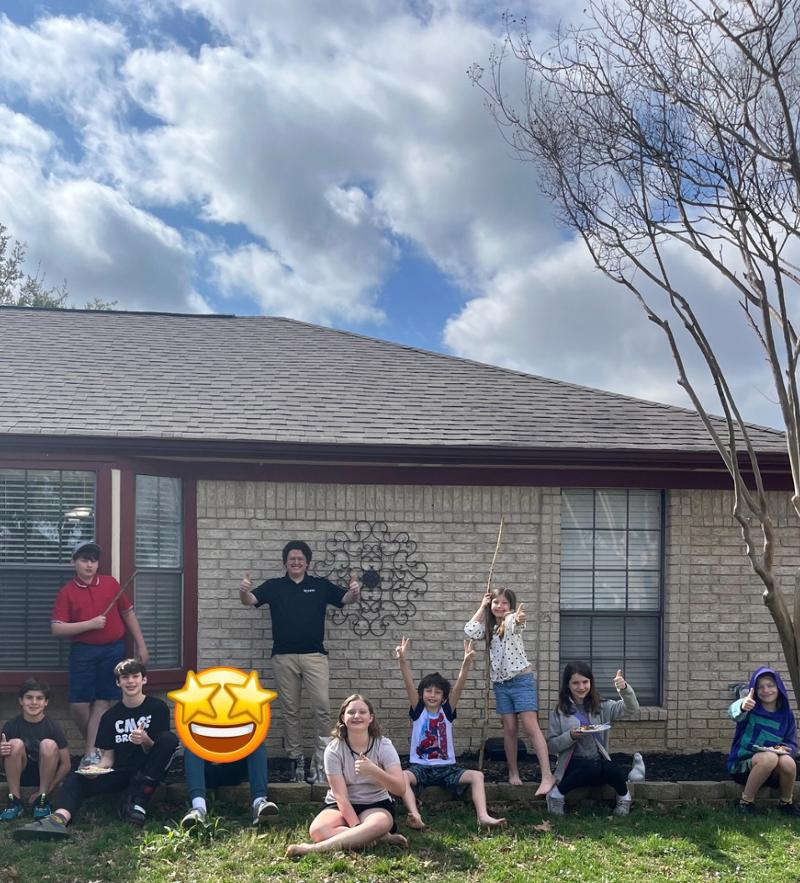 Several students and an instructor smiling outside a brick home.