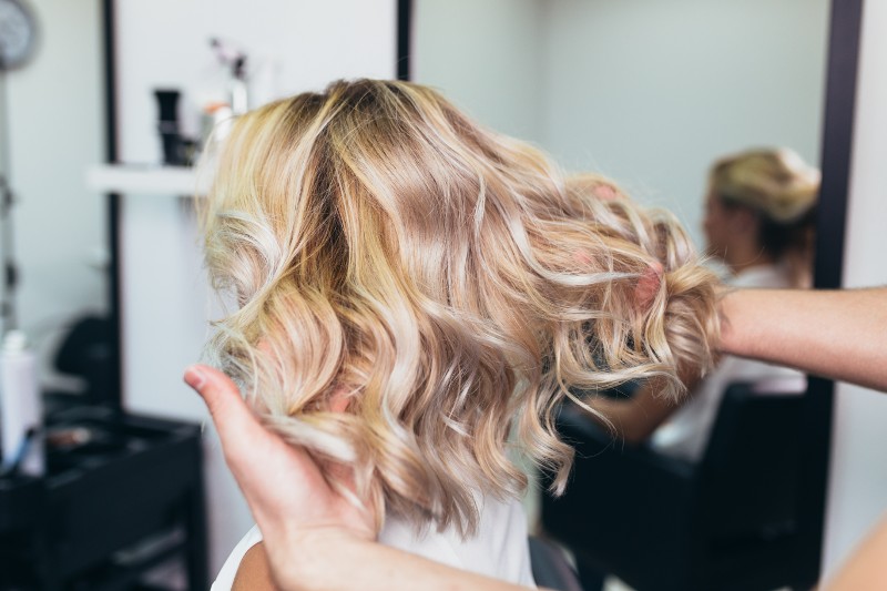 A woman with wavy blonde hair receives salon services