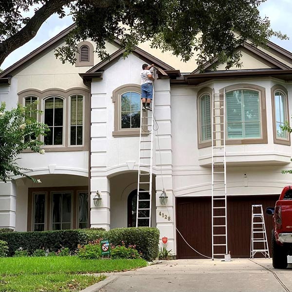 A worker paints the second story of a 2-story home