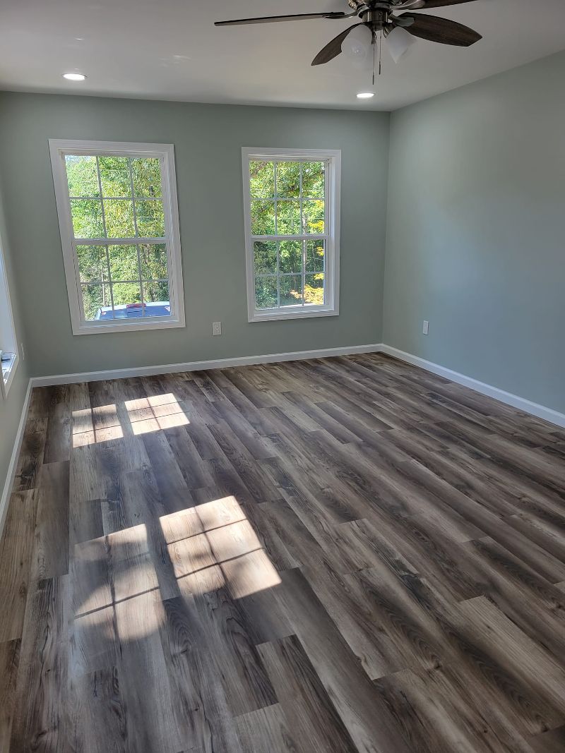 An open living room with new drywall and laminate flooring.