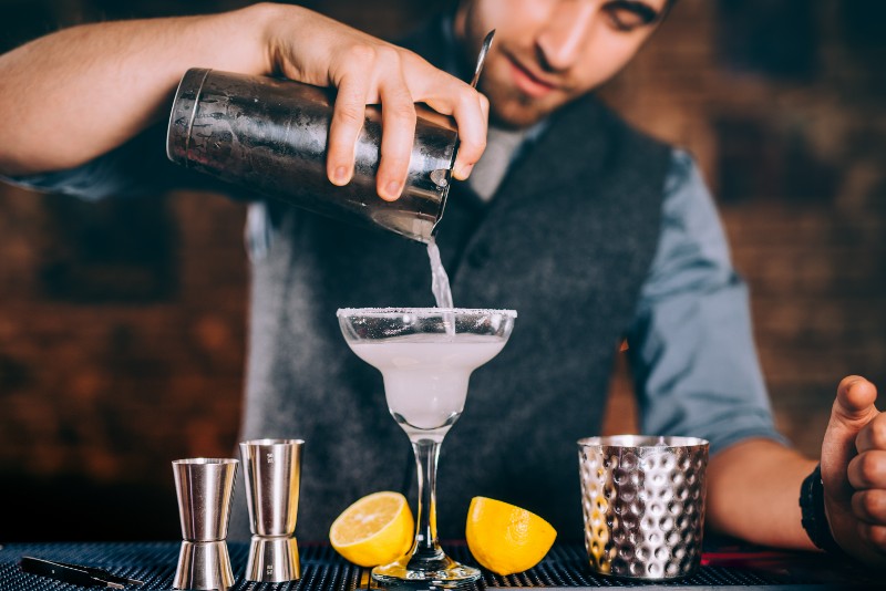 A mixologist pours a dink into a glass.