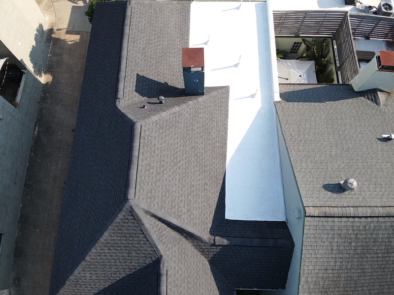 Overhead view of commercial building with grey shingles on roof.