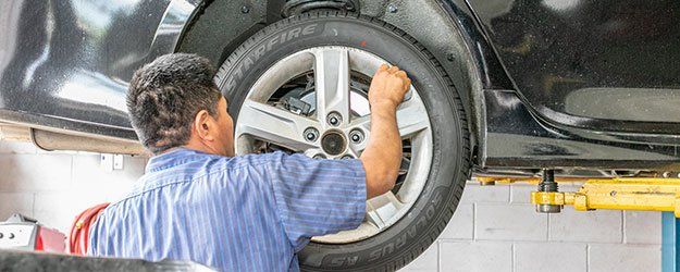 A worker inspects a car's tire