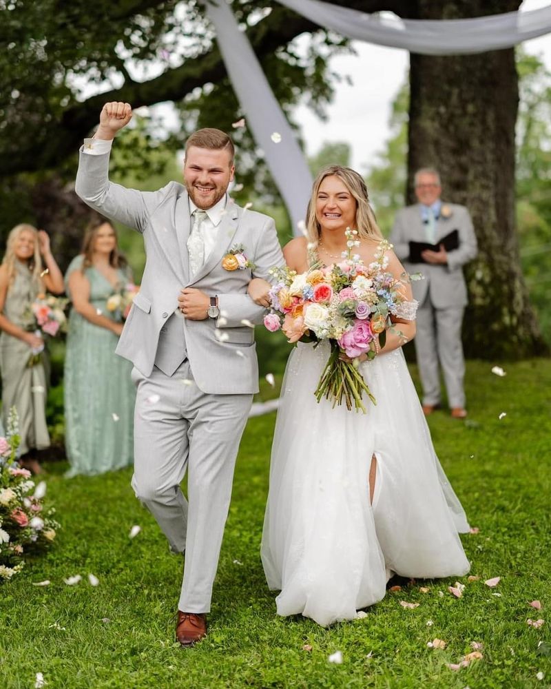 A husband and wife smile while leaving their wedding ceremony.