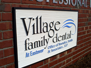 A plaque on a brick wall for Village Family Dental.