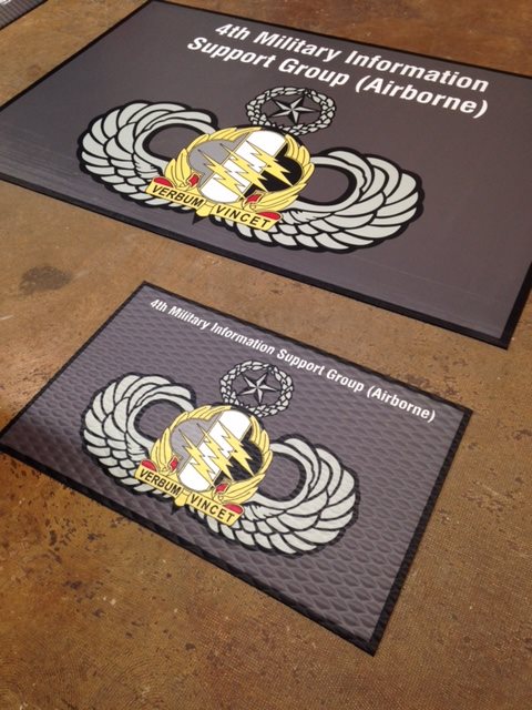 Two rectangular gray rugs with artwork for 4th Military Information Support Group (Airborne).