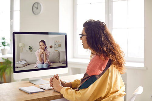 A woman looks at a computer screen for virtual psychotherapy sessions.