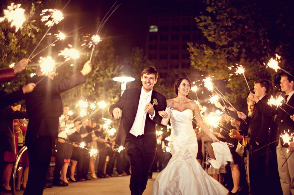 A bride and groom walk through the a line of friends and family holding sparklers