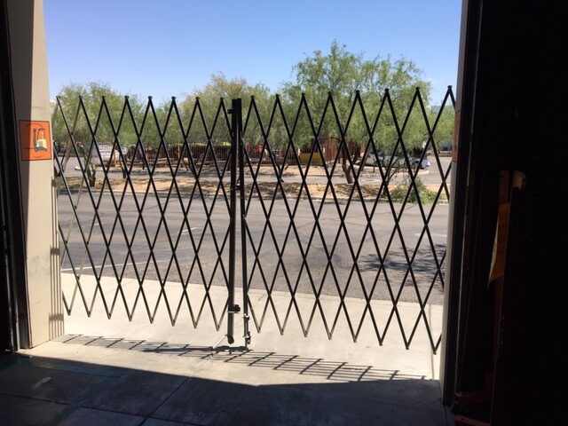 An accordian gate is closed blocking entrance to a warehouse.