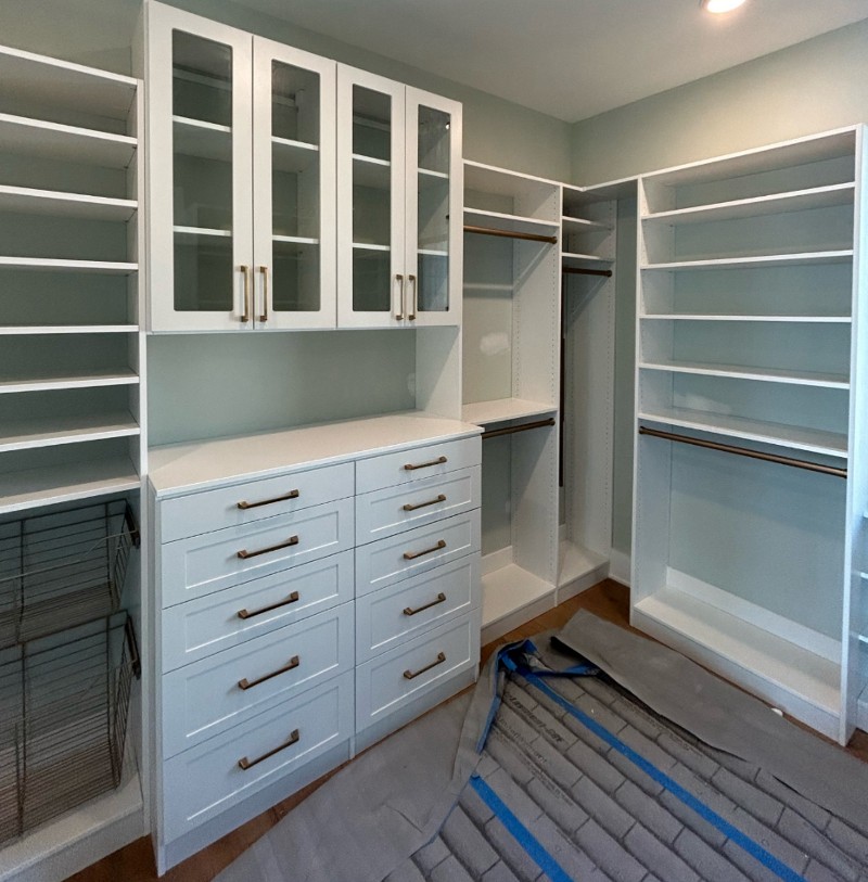 Open-shelf storage with a section of drawers in the middle at the bottom and glass doors at the top.