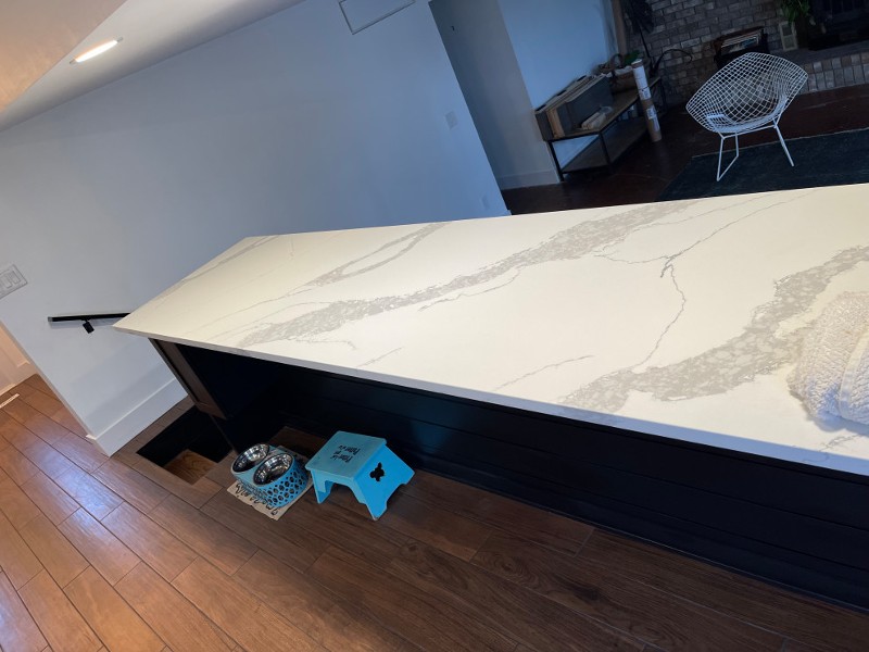An island with a white granite countertop is being installed in a kitchen.