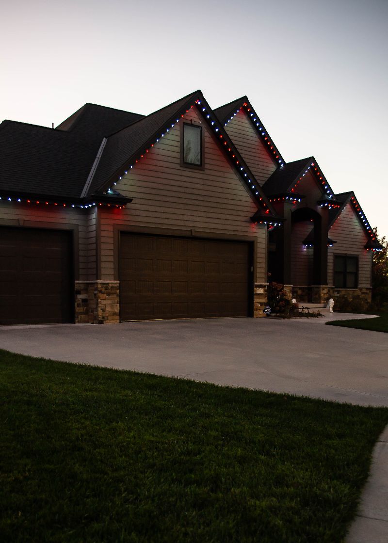 Trimlight lighting set to red and white on a brown home.