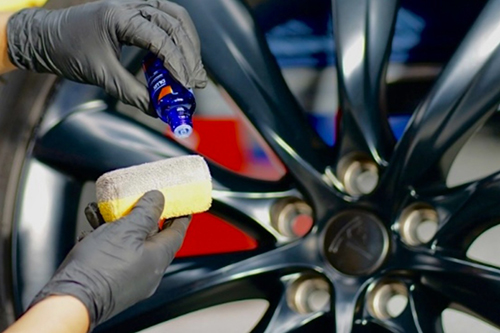 A man applies polish to car’s rim.