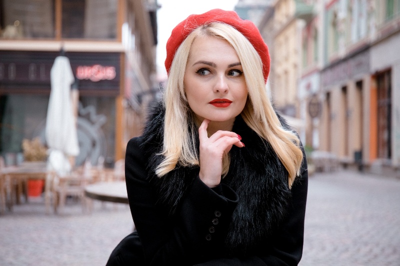 A blonde woman in a black coat and red hat