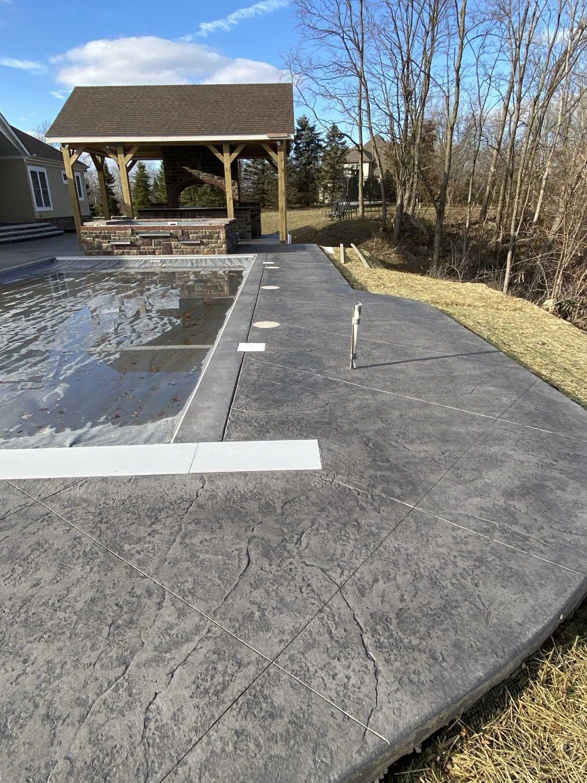 A rectangular pool is surrounded by stamped concrete.