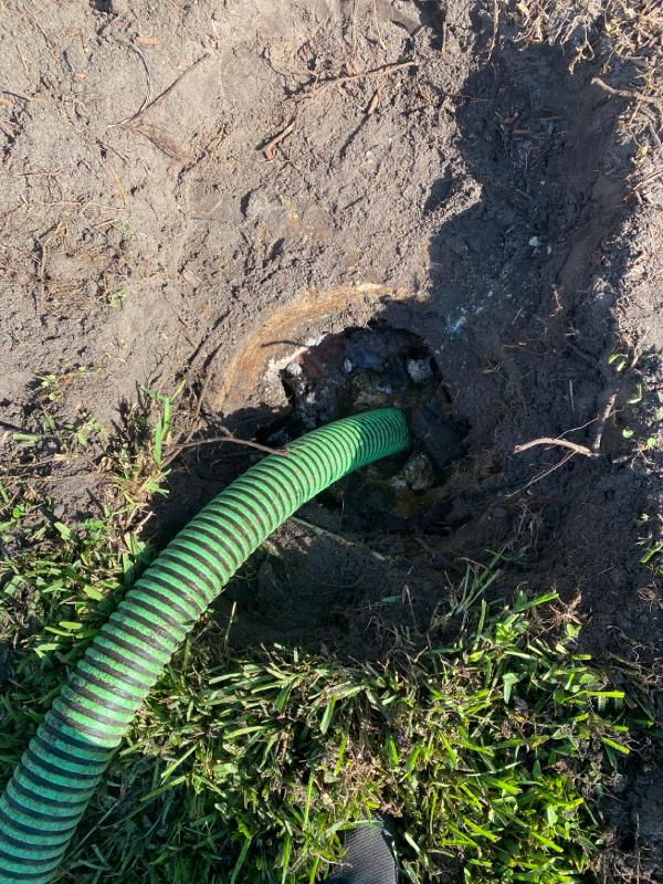 A green hose is inserted into a septic system.