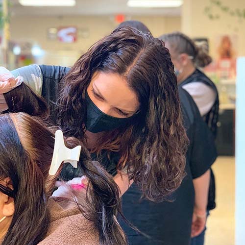 A student works on a girl’s hair.