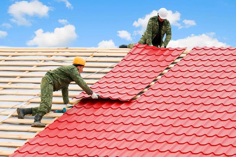 Two men attach roofing panels onto a new roof.