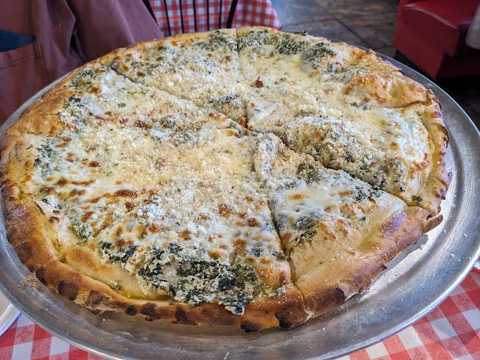 Fresh four-cheese pizza, topped with spinach and finished with a perfectly browned crust