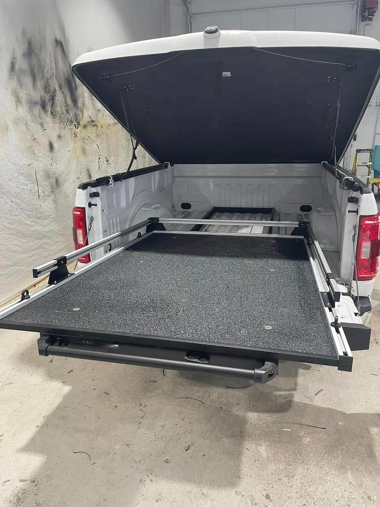Tonneau cover and roll-out truck bed in a white pickup.