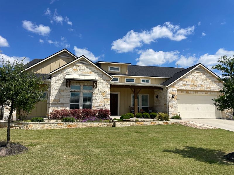 The view from the lawn of a ranch home with a shingled roof.